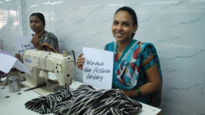 Productora de Comercio Justo con un cartel del Fashion Revolution Day , preguntando quién hizo tus prendas?